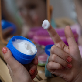 Una niña con una crema para la cara.