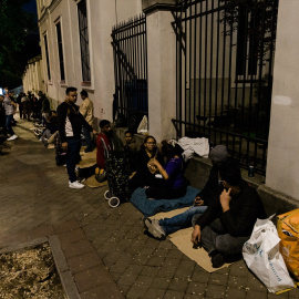 Varias personas hacen cola nocturna para conseguir el certificado de vulnerabilidad en una Oficina de Asistencia en Materia de Registro, a 21 de abril de 2026, en Madrid.