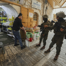 Soldados israelíes increpan al dueño de una tienda palestina en la ciudad de Hebrón, en la Cisjordania ocupada.