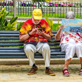 Una pareja de turistas consultan un mapa en un banco de Cádiz.
