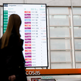 Viajeros en la Estación de Atocha de Madrid frente a un panel de salidas, encabezado por Sevilla.