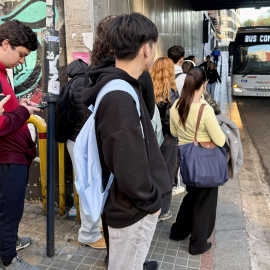 Usuaris veient com s'apropa un bus de la línia E3 a la parada de l'estació de Cerdanyola amb el cartell de 'bus complet'.  15/5/2026