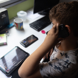 Foto de archivo de un niño usando el teléfono móvil y una tablet.
