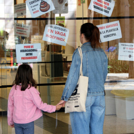 Dues usuàries davant la porta tancada de la biblioteca Montserrat Abelló, a les Corts