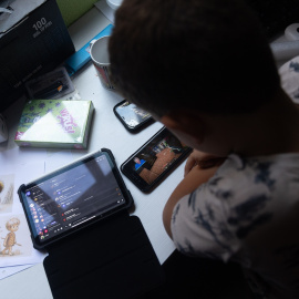Foto de archivo de un niño usando el teléfono móvil y una tablet.