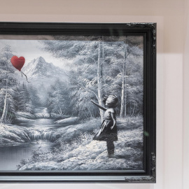 Fotografía del óleo del artista Banksy que representa a una niña a la que se le escapa un globo rojo.
