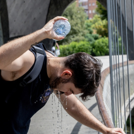 Un chico se moja la cabeza a causa del calor.
