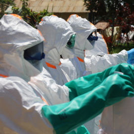Trabajadores médicos visten trajes de protección antes de desinfectar una zona en Mongbwalu.