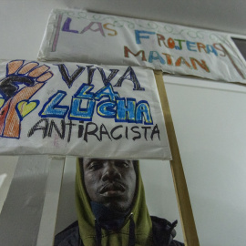 Una persona entre pancartas durante un acto de conmemoración por el aniversario de la tragedia de la playa de El Tarajal.