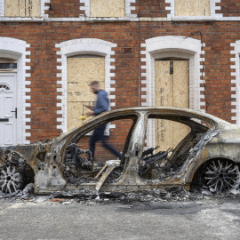 Un hombre pasa frente a un coche calcinado este miércoles en Belfast.
