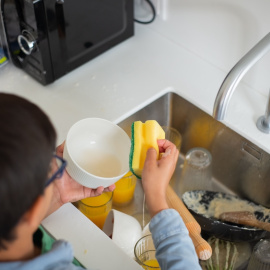 Imagen de un niño ayudando a fregar los platos.