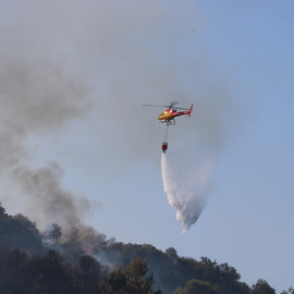 Un helicóptero apagafuegos suelta una carga de agua sobre el incendio de Sant Quirze de Safaja, en Barcelona.