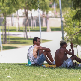Varias personas se sientan a la sombra para refrescarse de las altas temperaturas, en una imagen de archivo.