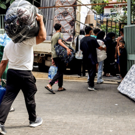 Libaneses desplazados cargan sus pertenencias en un camión mientras se preparan para dejar la escuela en la que se habían estado cobijando.
