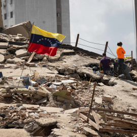 Voluntarios realizan labores de búsqueda en los escombros de un edificio este lunes, en La Guaira (Venezuela).