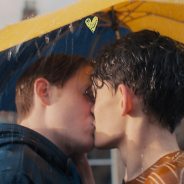 Nick y Charlie, protagonistas de 'Heartstopper' se dan un beso bajo la lluvia.