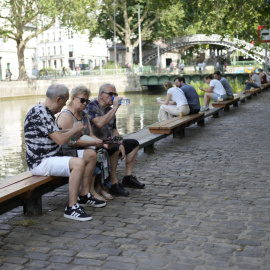 Varias personas descansan a orillas del Sena en París durante la ola de calor.