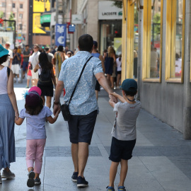 Una familia pasea de la mano por una calle de Madrid.