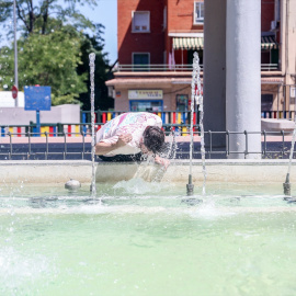 Una persona se refresca en una fuente en Madrid.