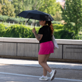 Una persona se refugia del sol con un paraguas frente a la ola de calor en Madrid.
