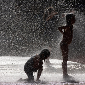 Dos niños se refrescan el pasado domimgo en un parque público de Fráncfort (Alemania).