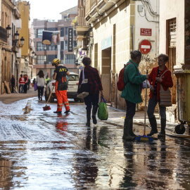 Varias personas en una calle cubierta de barro, a 28 de noviembre de 2024, en Paiporta, Valencia.