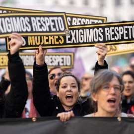 Varias personas sujetan carteles en la manifestación del 25N.