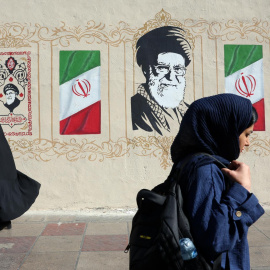 Mujeres iraníes caminan junto a un mural del difunto Líder Supremo iraní, el ayatolá Ali Jamenei, en una calle de Teherán, Irán.