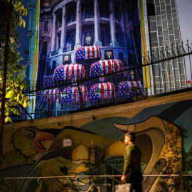 Un hombre a unos metros de un mural de protesta iraní que muestra al presidente estadounidense, Donald Trump, en un ataúd, en el centro de Teherán (Irán).