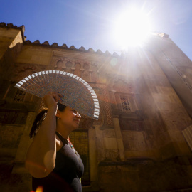 Una mujer se protege con un abanico para aliviar las altas temperatura en Córdoba.