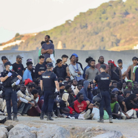 Personas migrantes y agentes de Policía en la playa ‘El Trampolín’ de Ceuta