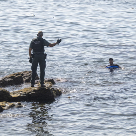 Un guardia civil junto a una persona en el mar, a 2 de agosto de 2026, en la frontera de Ceuta.