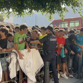 Menores migrantes esperan a las puertas de la Jefatura Superior de Policía de Ceuta para que ser registrados.