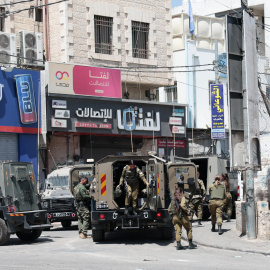 Vehículos del Ejército israelí (FDI) en la entrada del campo de refugiados de Qalandia, frente a la sede de la UNRWA, al norte de Jerusalén durante una redada (05/08/2026)