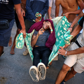 Migrantes transportan a otro migrante, quien según afirman resultó herido cuando la policía y el ejército españoles intentaron contenerlos en una zona de la playa.