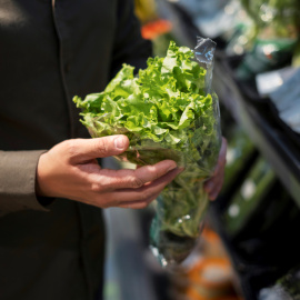 Una persona sostiene una lechuga en el supermercado.