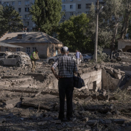 Una persona junto a coches y edificios dañados en el ataque ruso contra Kiev, el 20 de agosto de 2026, en medio de la invasión rusa de Ucrania.