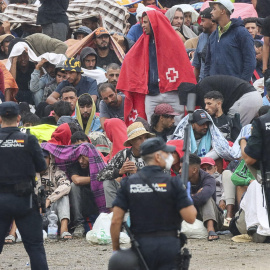 La policía vigila a migrantes en la playa de El Trampolín en Ceuta, este viernes.