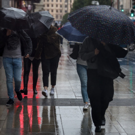 Transeúntes sufriendo los estragos del viento y la lluvia en una imagen de archivo.