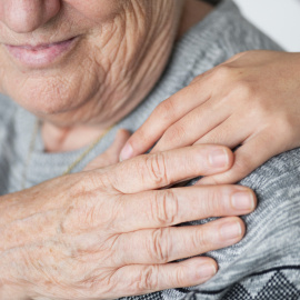 Un niño apoya su mano en el hombro de una persona anciana.