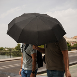 Personas paseando con sombrillas, a 23 de junio de 2026, en Sevilla.