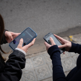 Dos niñas usan el teléfono móvil.