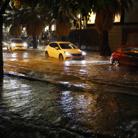 Coches circulan por una calle inundada tras las fuertes lluvias caídas en València.