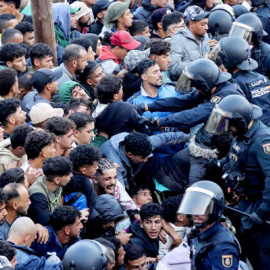 Policías cargan contra varias personas durante el traslado de migrantes en Ceuta.