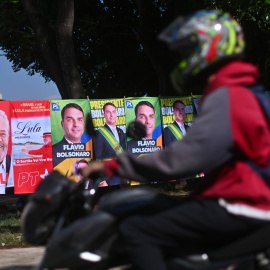 Una persona conduce su motocicleta frente a carteles de las elecciones brasileñas de este 4 de octubre de 2026.