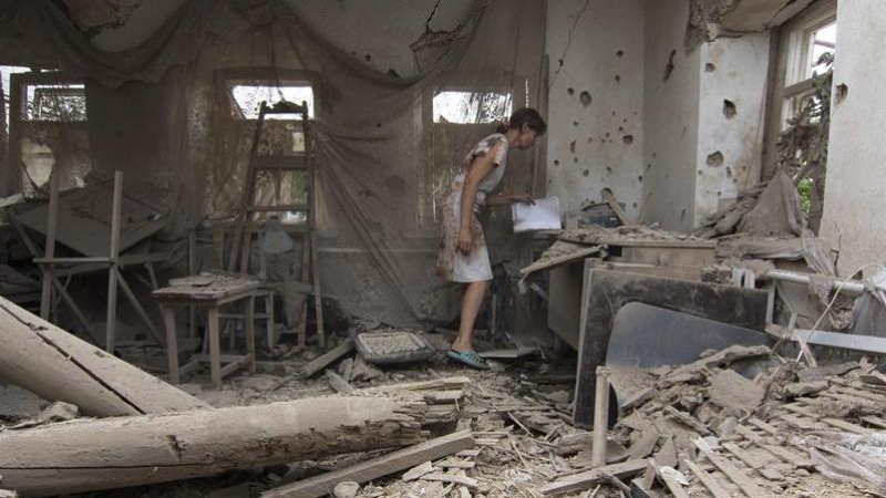 Una mujer revisa los restos de una casa tras un bombardeo en la localidad bajo control ucraniano de Sartana, cerca de la ciudad oriental de Mariupol (Ucrania) hoy, 17 de agosto de 2015. EFE/Sergey Vaganov