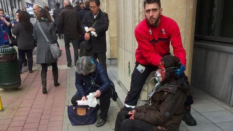 Un guardia de seguridad privada ayuda a una mujer herida en el atentado ocurrido en el metro de Bruselas.- AFP