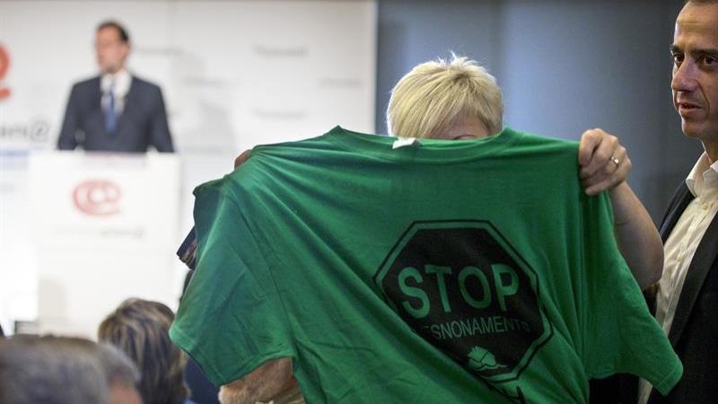 Una activista de la PAH muestra una camiseta alusiva a los desahucios durante intervención de Rajoy en Barcelona./ EFE