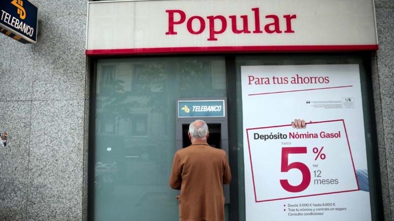 Un hombre retira dinero de un cajero de una sucursal del Banco Popular en Madrid. | EFE