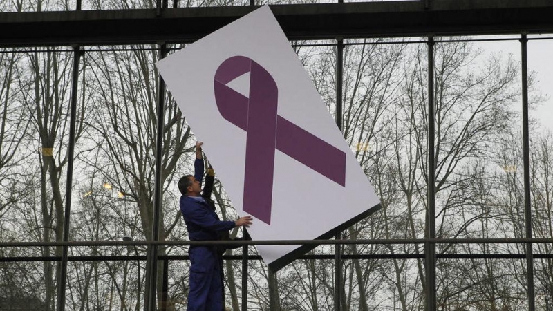 Un operario coloca un lazo de apoyo a las víctimas de violencia de género en la fachada del Ministerio de Sanidad. EFE